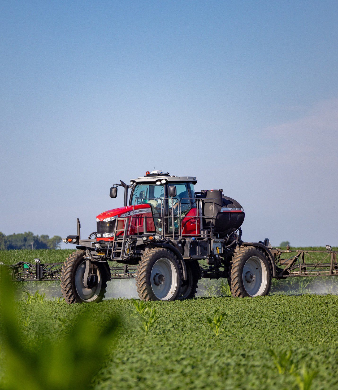 Picture17 Red self-propelled sprayer with wide booms applying spot spray over a green soybean field under blue sky, illustrating precision ag tools like autosteer, variable rate application, and WeedSeeker-style targeted herbicide application for improved yield and sustainability